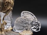 a glass rabbit figurine sitting next to a gold vase