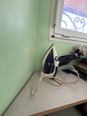 un fer à repasser posé sur une table près d'une fenêtre