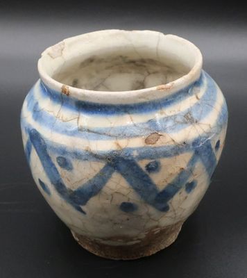 un petit vase bleu et blanc posé sur une surface noire