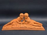 deux figurines représentant deux enfants allongés sur le sable