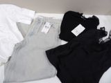 a white shirt, black top, and grey shorts on a bed