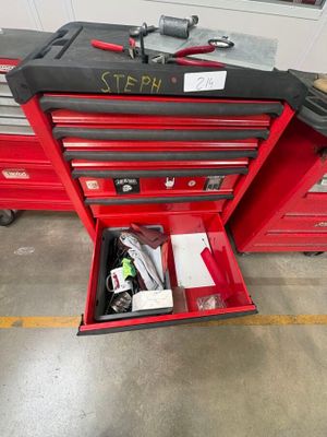 une boîte à outils rouge contenant des outils, dans un garage