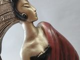 statue of a woman sitting on a crescent with a bird in her hand