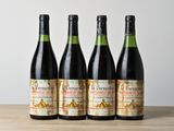 quatre bouteilles de vin sont posées sur une table en bois