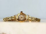 an image of a gold wrist watch sitting on top of a marble counter