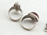 two silver rings with a red stone in them on a white surface