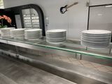 de nombreuses assiettes blanches posées sur une étagère en verre dans une cuisine