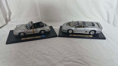 pair of silver model cars with open doors on black bases