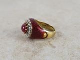 an image of a red and gold ring with diamonds on it