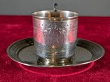 a silver cup and saucer on a red table cloth