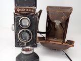 an old camera with a leather case next to it