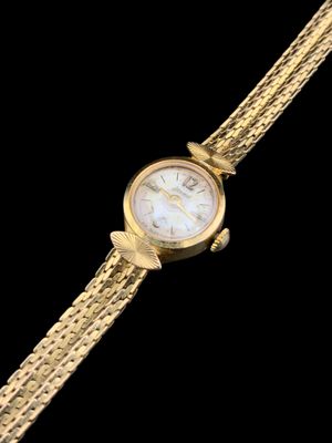 une image montrant un gros plan d'une montre en or sur fond noir