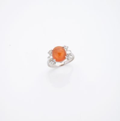 une bague sertie d'une pierre orange et de diamants, sur fond blanc