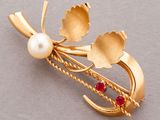 an image of a gold brooch with pearls and leaves