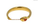 une photo d'un bracelet en forme de serpent en or, orné d'une pierre rouge au centre