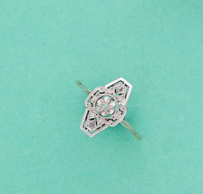 un gros plan d'une bague en diamant posée sur une surface verte