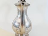 a silver vase with a bird on top of it