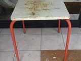 une petite table au plateau rouillé, devant un magasin