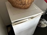 a wicker basket on top of a small refrigerator