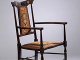 une chaise ancienne en bois avec une assise et des accoudoirs décorés de motifs
