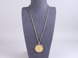 un collier composé d'une pièce d'or suspendue à une chaîne autour du cou d'un mannequin