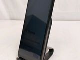 a black cell phone on a stand on a white surface