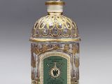 une bouteille en verre doré et vert, surmontée d'une horloge