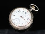 a pocket watch that is sitting on a black surface