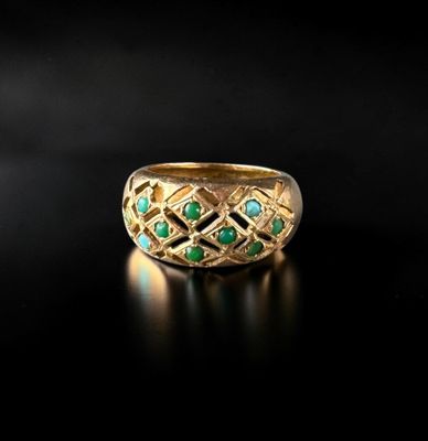 a close up of a gold ring with green stones