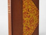 an old book with a brown cover sitting on top of a white table