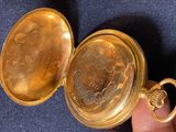 a person holding a gold pocket watch in their hand