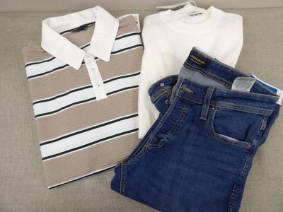 deux paires de jeans et un polo posés sur un canapé