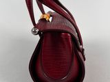 a close up of a red purse on a white surface