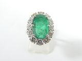 a close up of a ring with a green stone surrounded by diamonds