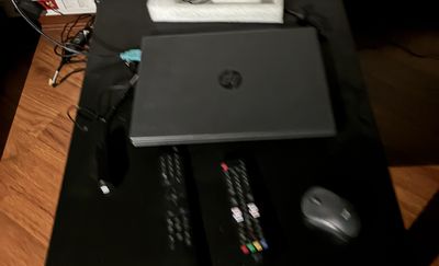 une table noire sur laquelle se trouvent un ordinateur portable, une souris et d'autres objets