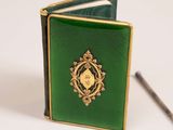 a small green book with a gold medallion on it