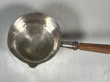 a silver pan with a wooden handle on a table