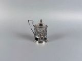 une théière ancienne en argent, dotée d'une anse, posée sur une surface blanche