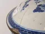 a blue and white bowl with a lid on a glass shelf