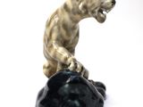 a figurine of a bear on a rock on a white background