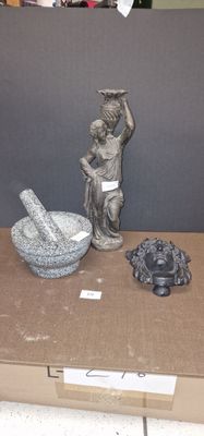 une boîte sur laquelle est posée une statue représentant un homme tenant un mortier et un bol