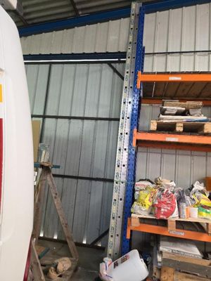 une camionnette blanche garée dans un garage dont les étagères sont remplies d'objets