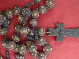 un tas de perles et une croix posés sur un tissu rouge