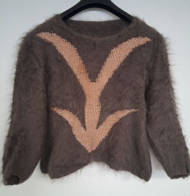 un pull marron orné d'un motif orange et blanc, suspendu à un cintre