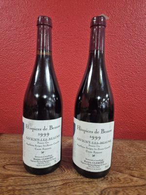 Deux bouteilles de vin sont posées sur une table devant un mur rouge.