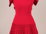une robe rouge posée sur un socle de mannequin, avec un mannequin blanc
