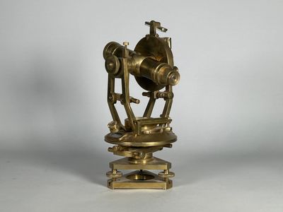 un télescope ancien en laiton posé sur un socle, sur fond blanc