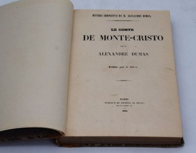 un livre ouvert posé sur une table, à côté d'une nappe blanche