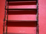 une étagère en bois comportant trois tablettes, adossée à un mur rouge