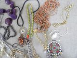 many different necklaces and bracelets laid out on a table